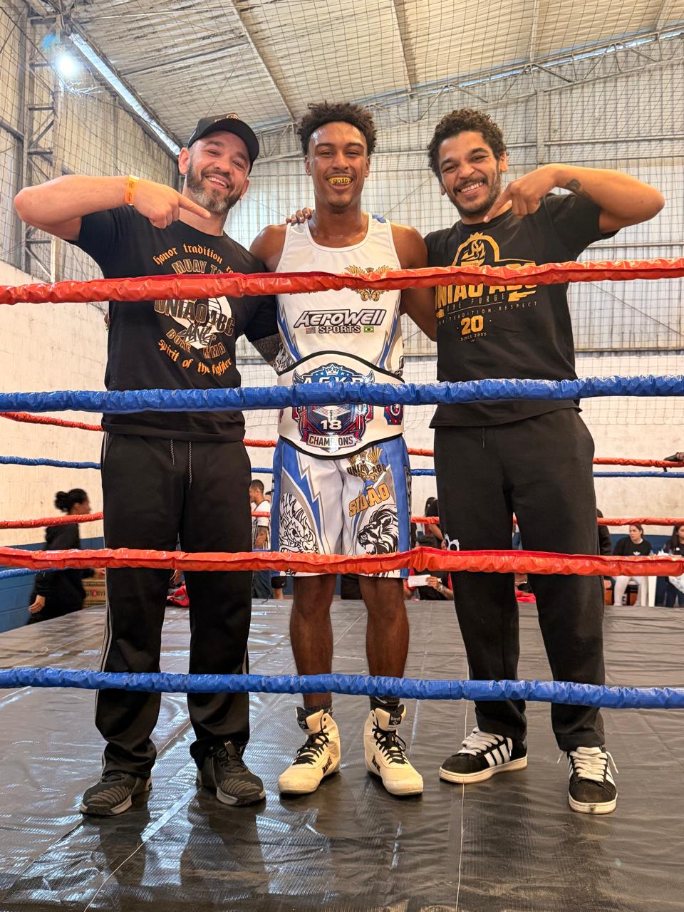 SIDão — campeão com cinturão ao lado dos treinadores no ringue